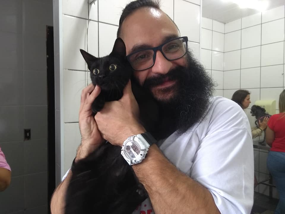 Dr. Saulo Godoy Chigo segurando um gato preto na clínica veterinária